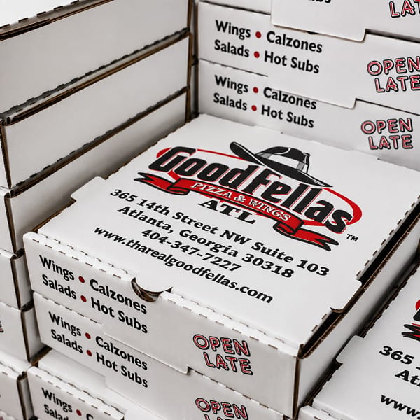 Stacked Goodfellas Pizza & Wings boxes display the Atlanta address, menu items, website, and “Open Late” branding.