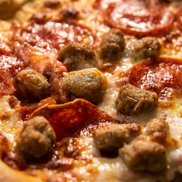 Close-up of a pepperoni and sausage pizza with melted cheese and a golden crust.