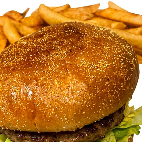 A close-up of a juicy burger with lettuce and a side of golden french fries.